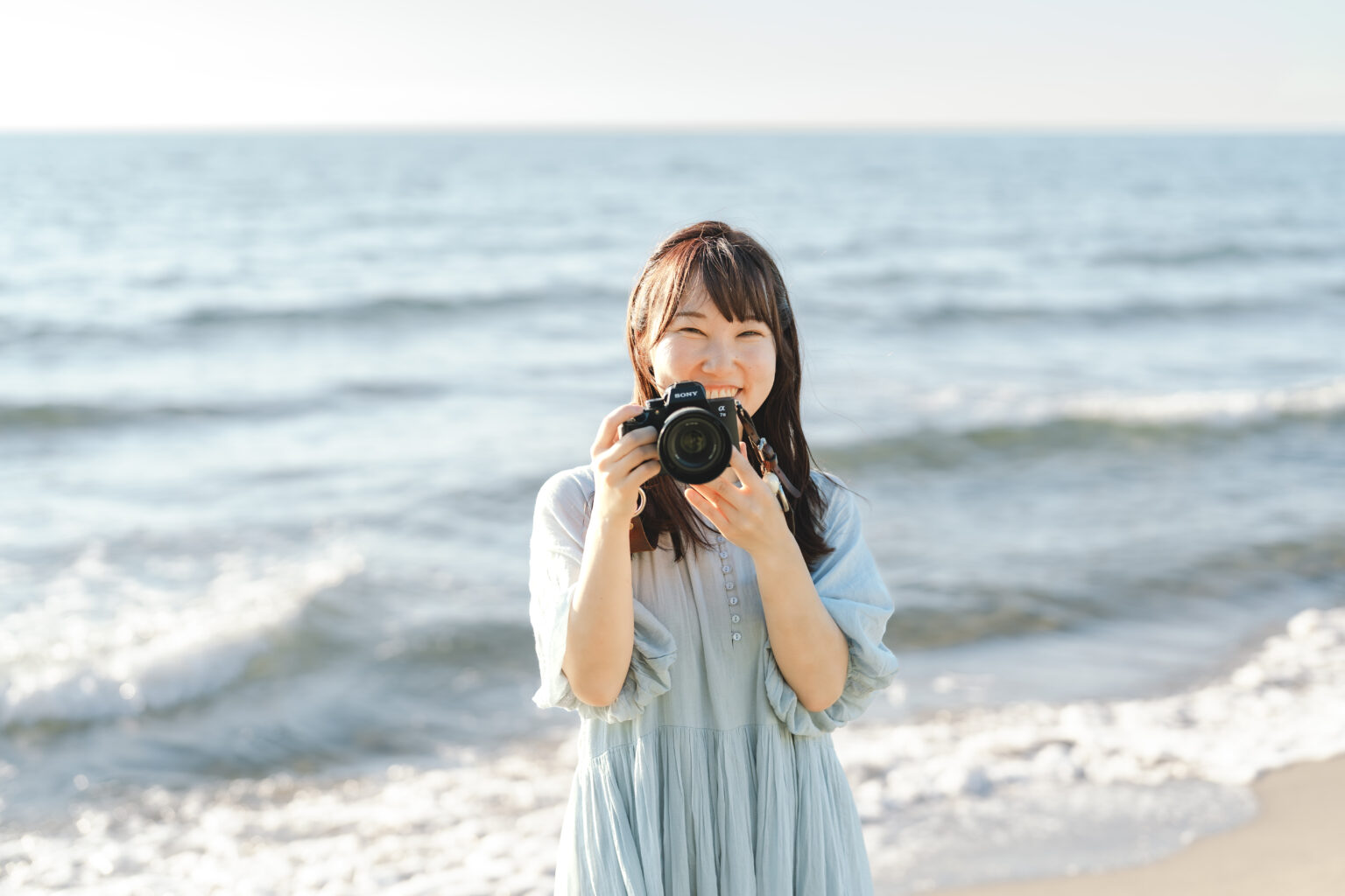 海辺でカメラを持つフォトグラファー阿部悠佳
